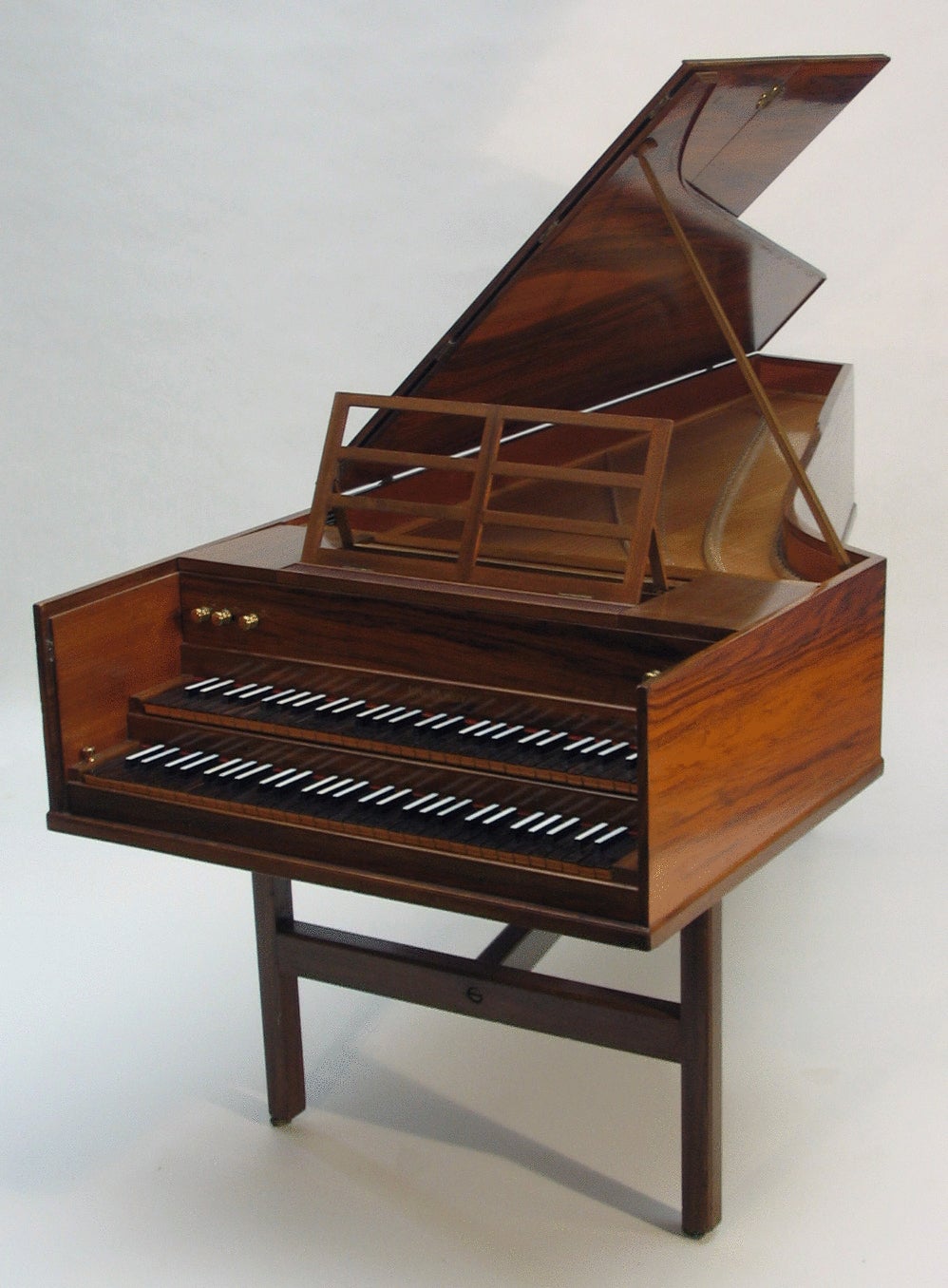 John Morley double manual harpsichord after Kirkmann, 2 x 8', 1 x 4' with lute and buff in walnut on trestle stand raised on brass casters, with hand stops. 

Compass : 5 octaves F - F .
No.116, circa 1958.

Made in England.