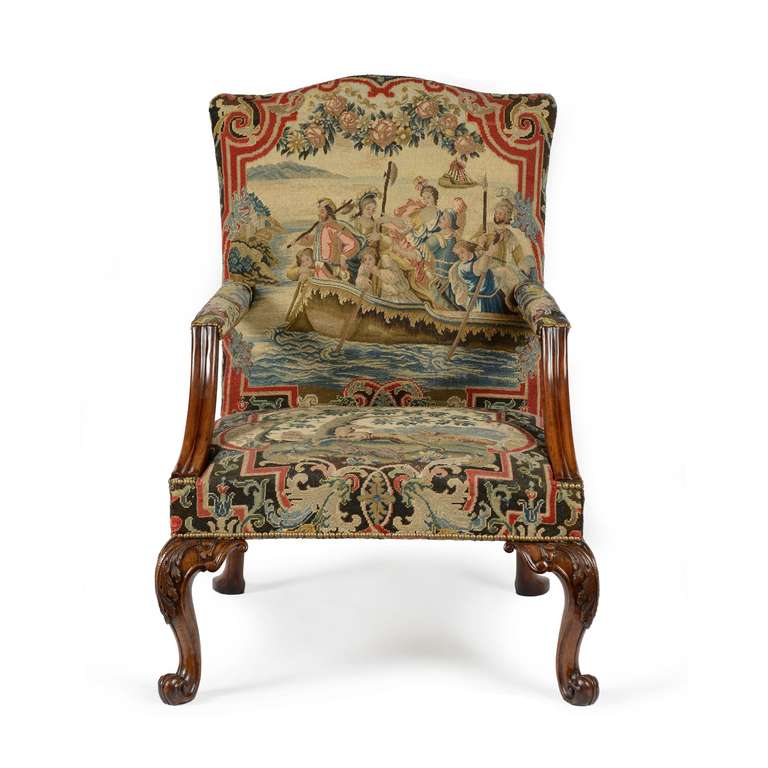 A superb George II carved mahogany and needlework armchair in the manner of Matthias Lock. The rectangular shaped needlework covered back with serpentine shaped top with needlework arms emanating from a midpoint on the back side rails, moulded and