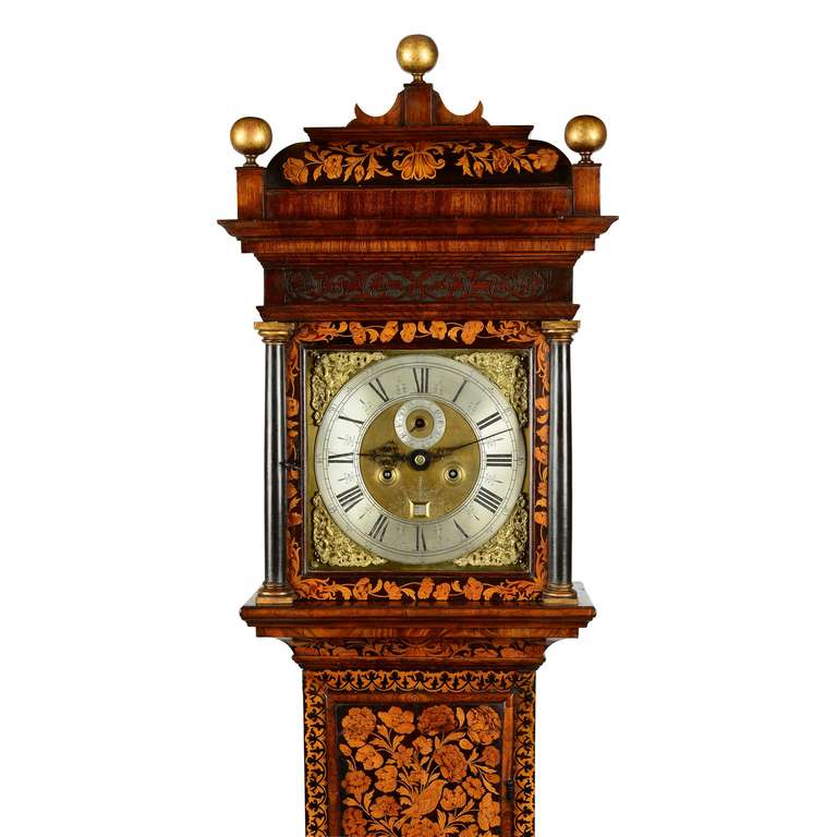 A William & Mary walnut and floral marquetry longcase clock by John Clowes, London. The five finned pillar outside countwheel, bell striking movement with 11 inch square brass dial with subsidiary seconds dial, ringed winding holes and scroll