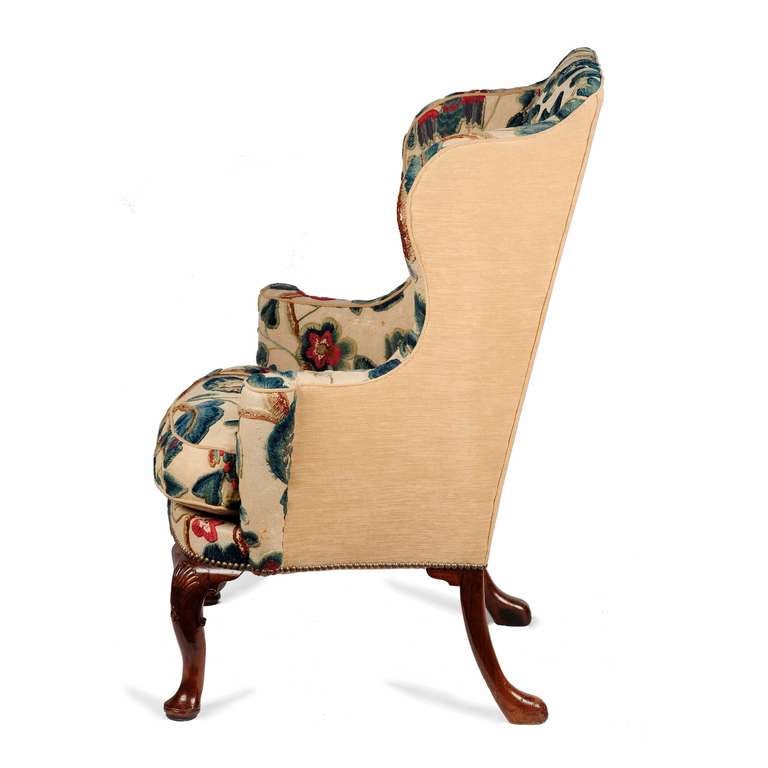 A superb George I carved walnut wing back armchair. The tall backrest with well shaped sides scrolling down seamlessly to well accentuated out-scrolled arms. 

The chair has elegant front cabriole legs with a crisply carved shell with bell flowers