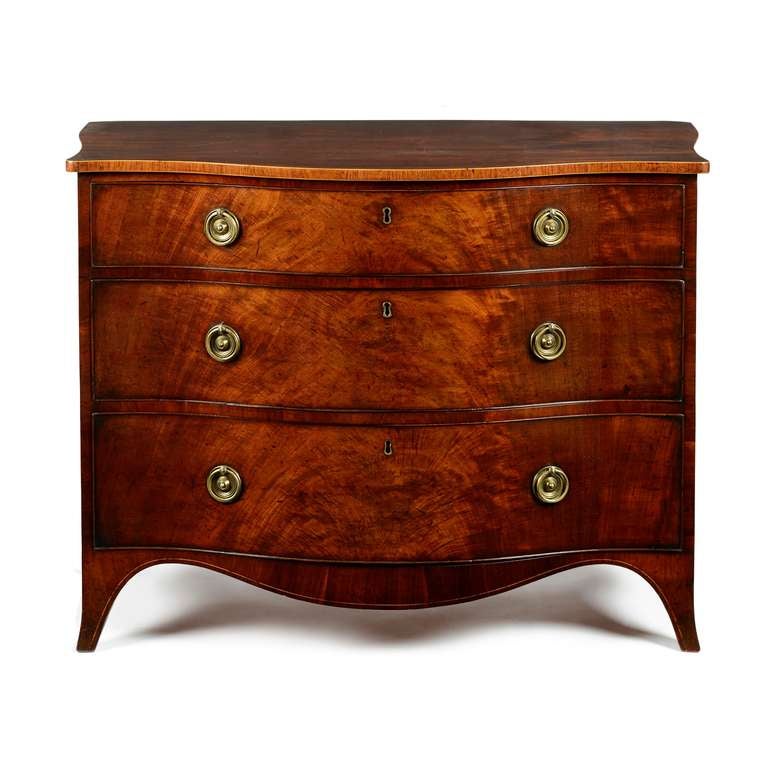 A fine, George III, Sheraton period, mahogany, serpentine dressing commode laid with well figured veneers and of excellent color and patina throughout. The serpentine fronted top with shaped sides, the edges banded in mahogany and strung with box.
