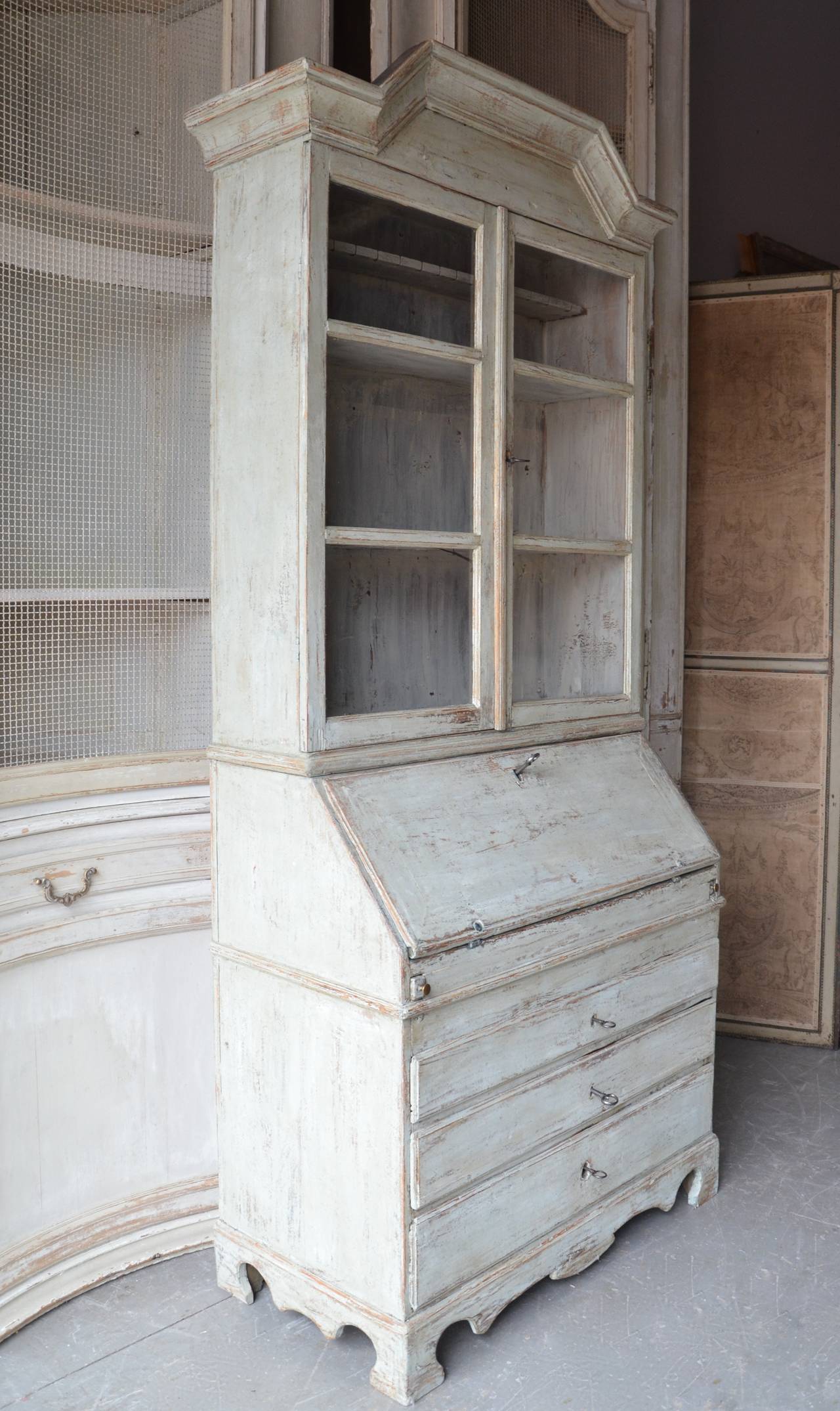 A very fine example of 18th century large secretaire cabinet of transition from Rococo to Gustavian period with a high arching pediment cornice and rare vitrine glass display bookcase. The fall front desk with multitude of drawers and compartments