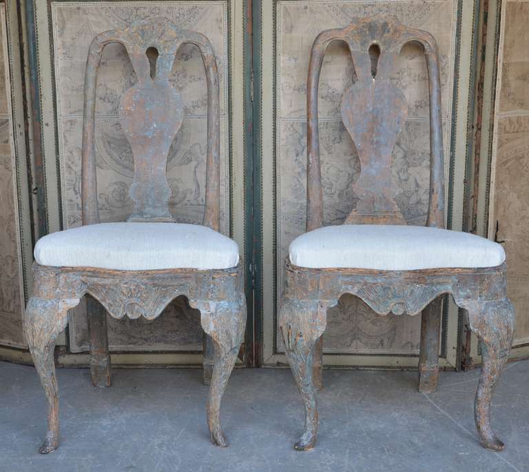 Pair of 18th century Swedish chairs,  in Rococo period  circa 1740-1750 with rocaille carving on the seat rails and pierced splats. Hand scraped back to traces of their original worn blue paint.
Seat covered with heavy hand loom antique linen.