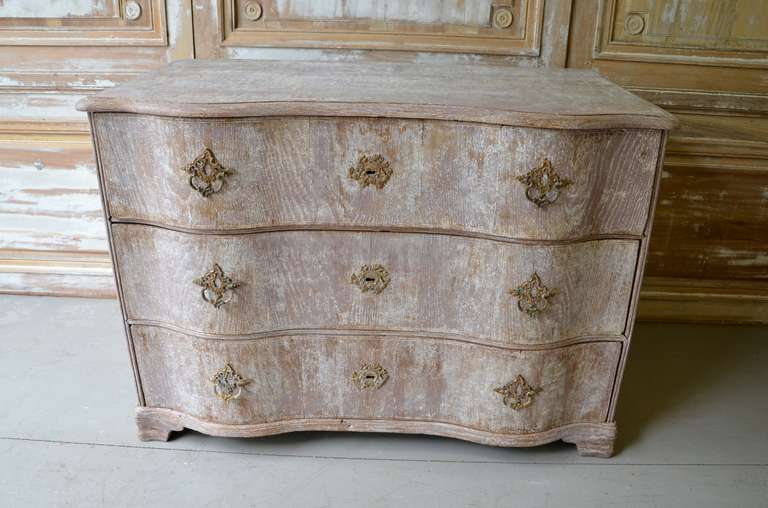 18th century Baroque commode with serpentine front and three drawers resting on short ogee bracket feet