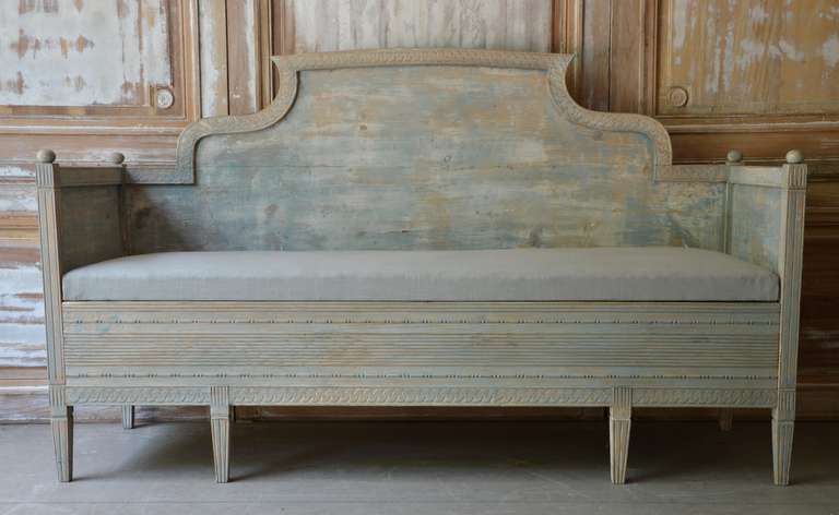 Gustavian sofa bed, Sweden circa 1850 with beautiful Gustavian details; the back and apron with standing stylized leaf carving and the leaf carving on the legs and columns. The finish has been scraped to reveal much of the original pale blue paint.