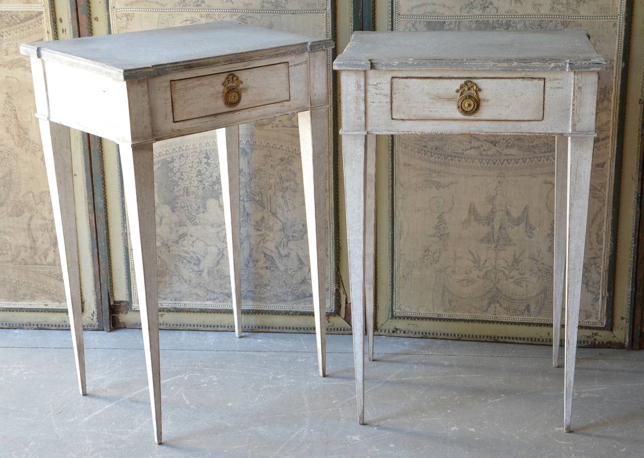 A charming pair of Swedish Gustavian side tables with front drawer with classical beautiful hardware, shaped top and slender tapered legs.