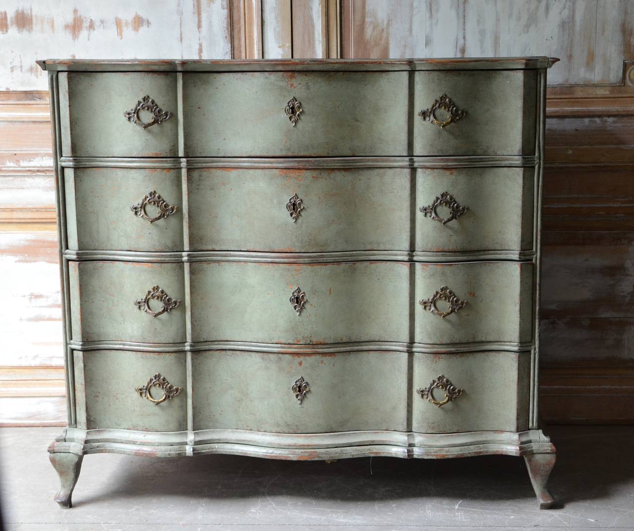 An exquisite and richly carved serpentine fronted late Baroque Swedish chest with rare double serpentine moldings on the drawers on stands and beautiful original brass hardwares, in greenish patina. Sweden, circa 1750.
