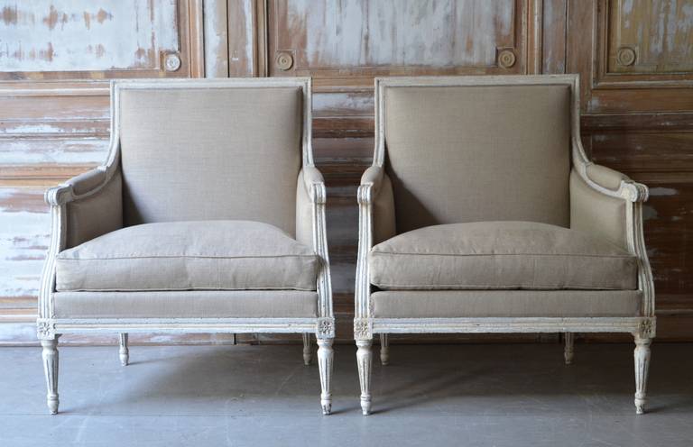Pair of Louis XVI Style Painted Large Bergères, France circa 1900

 A pair of French painted  Bergères in Louis XVI taste, with generous seats. 
The wood frames are in lovely blue-gray painted finish with fluted leg and cubic blocks decorated