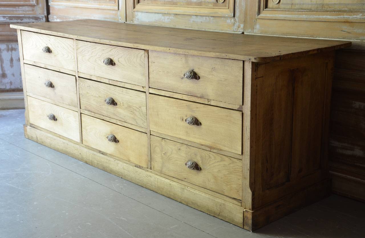 A huge 19th century sale counter/commode with nine large drawers and brass pulls in patinated oak.