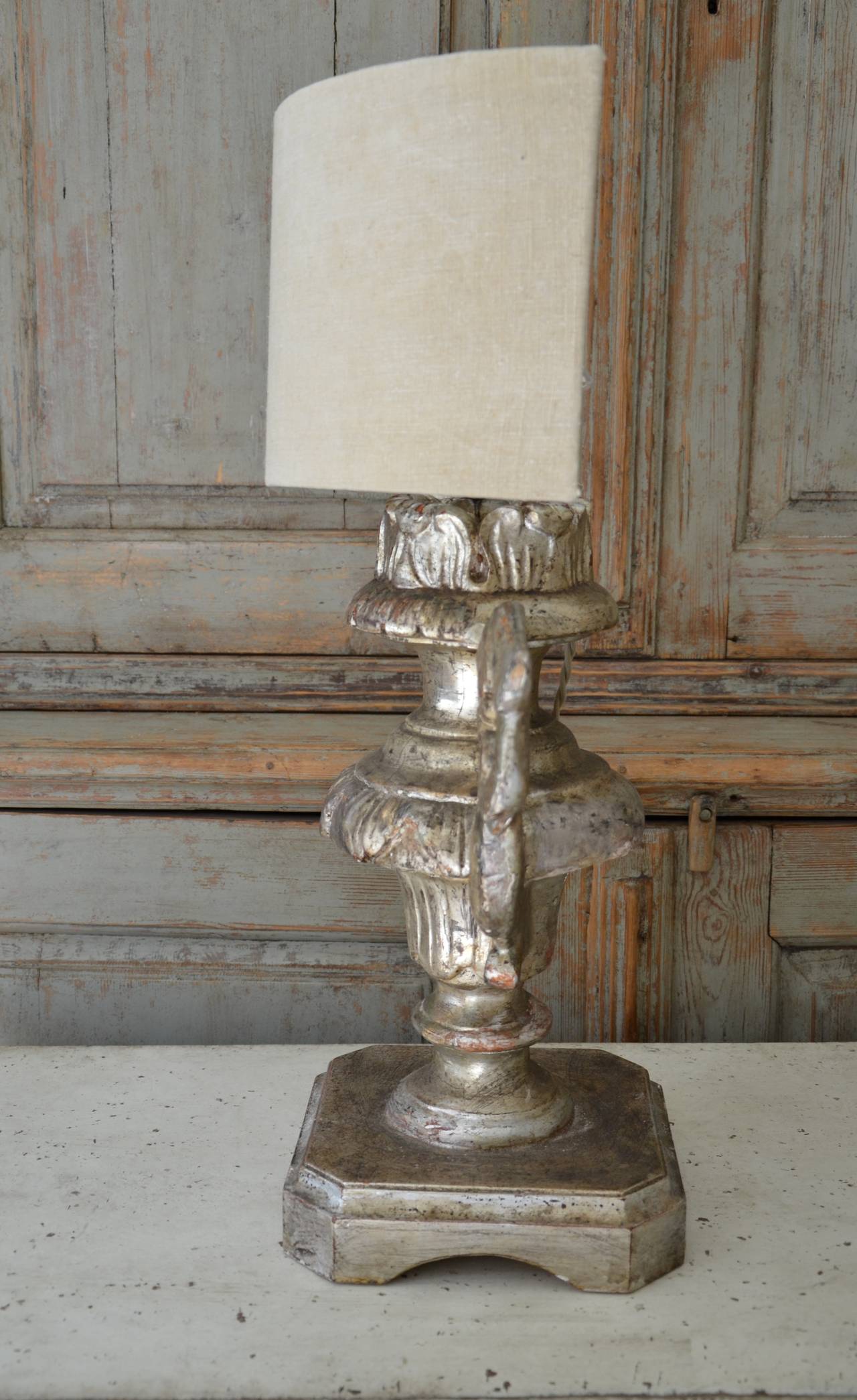 Pair of Italian 18th century candle holders in patinated silver giltwood with beautifully carved urn shape made as lamps with custom-made half shape linen shade. Classic and timeless for any decor.
Measures: Shade 14