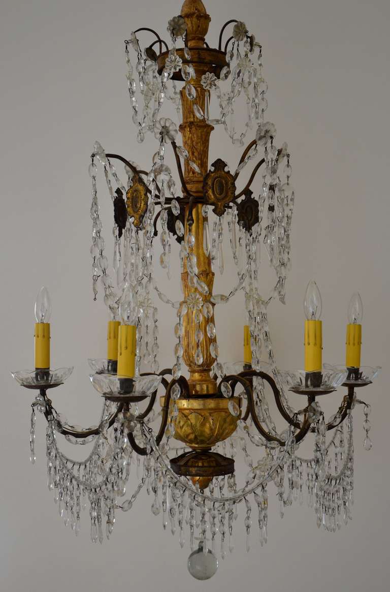 Early 19th century Italian Gilt Wood and Iron Chandelier with six arms, three tiers with crystal drops, rosettes, swags and patinated pressed tole medallions.
Electrified for USA standards.