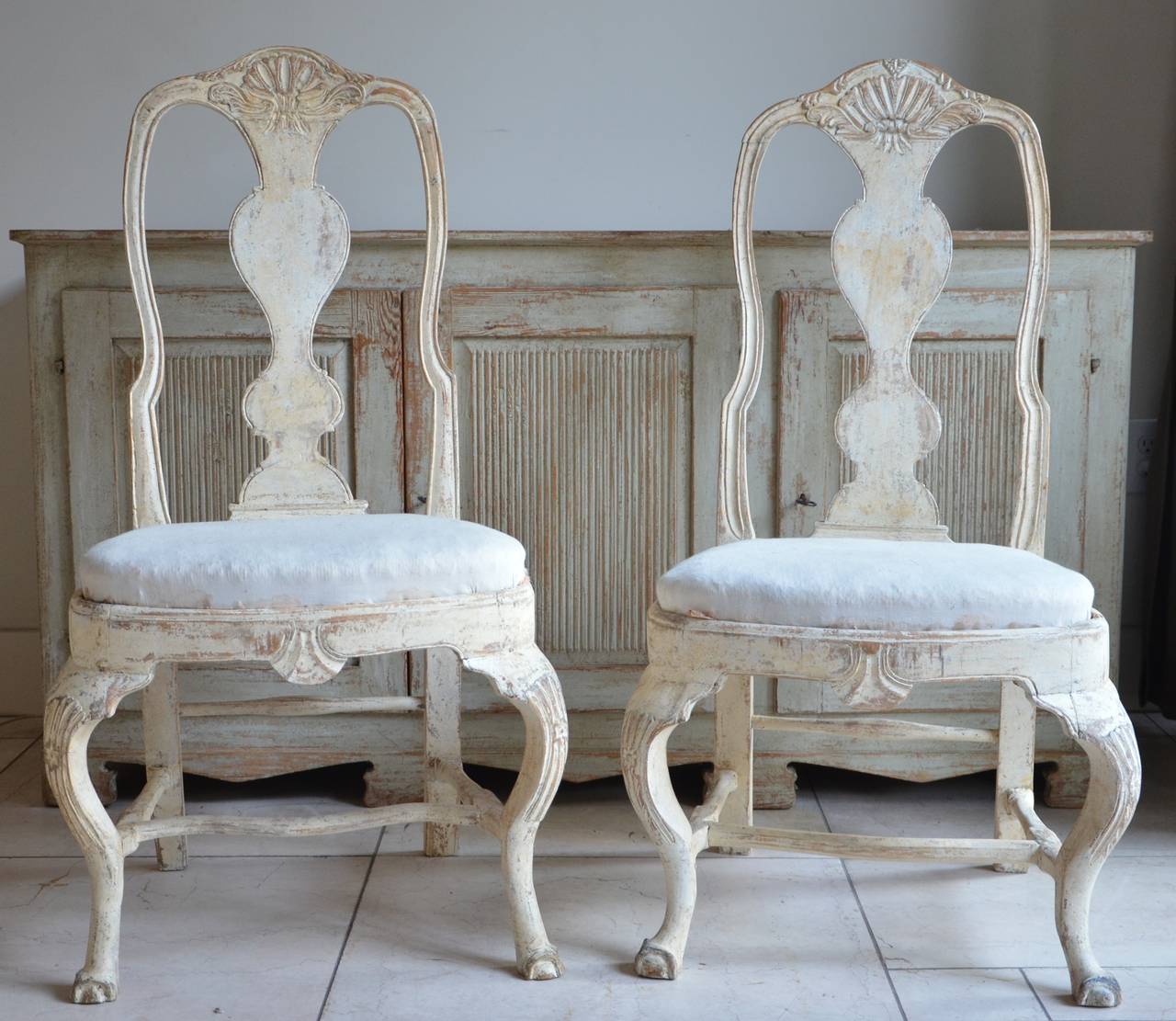 Pair of 18th century Swedish chairs, in Rococo period circa 1760 with rocaille carving on the seat rails and pierced splats. Hand scraped back to traces of their original worn cream paint.
Lovengly hand made and just with little difference in