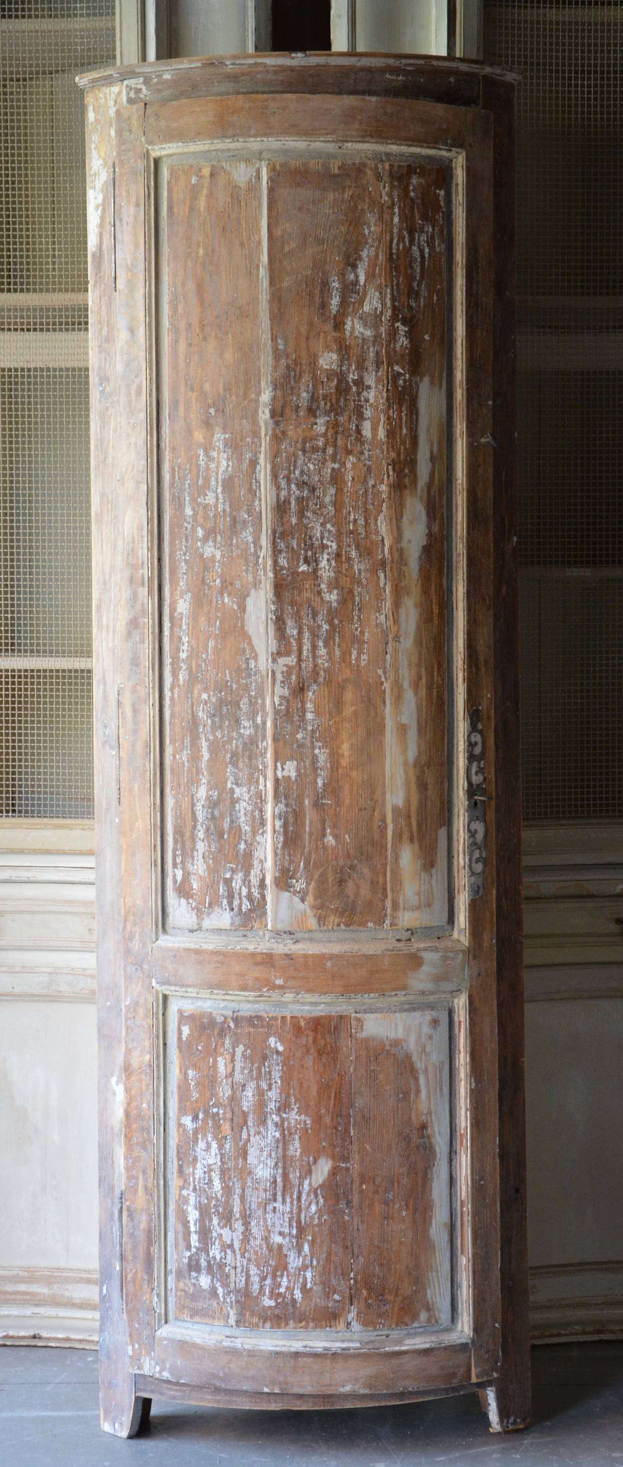 19th century French Louis XV style corner cabinet with careful demilune shape paneled door front craped back to traces of its original paint.
France, circa 1860.