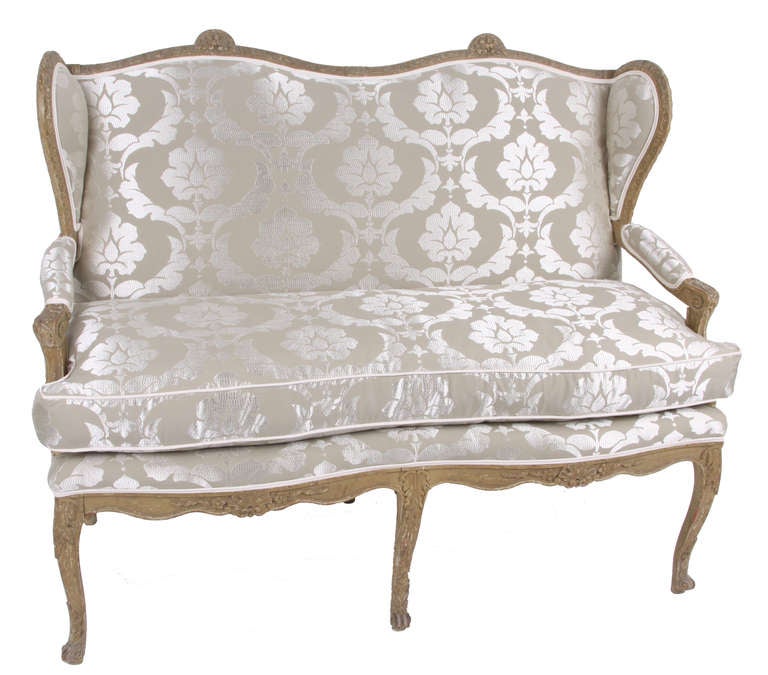 A gorgeous 1860 French settee with a uniquely hand carved wood frame with fine detailing. The settee has been newly upholstered in an embroidered silk damask imported from France. This piece is truly stunning from every angle.