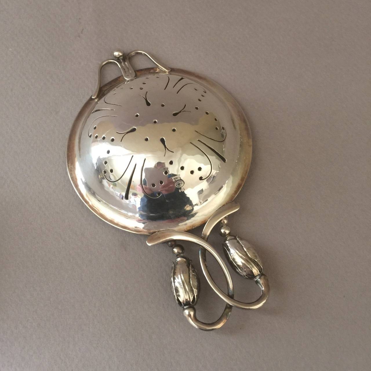 Georg Jensen Blossom Tea Strainer on Stand

Exquisitely handmade with scrolled handle terminating into two blossoms on a pierced bowl. Strainer sits perfectly on footed blossom stand. Hand hammered and in excellent condition.

Sterling silver,