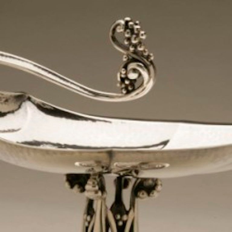 Georg Jensen Sterling Silver Compote No. 285A

Exceptionally rare Georg Jensen candy dish designed in 1918. On a stepped circular base, rising to a foliate openwork stem, the bowl formed as a stylized hand-hammered shell with vine-shaped handle