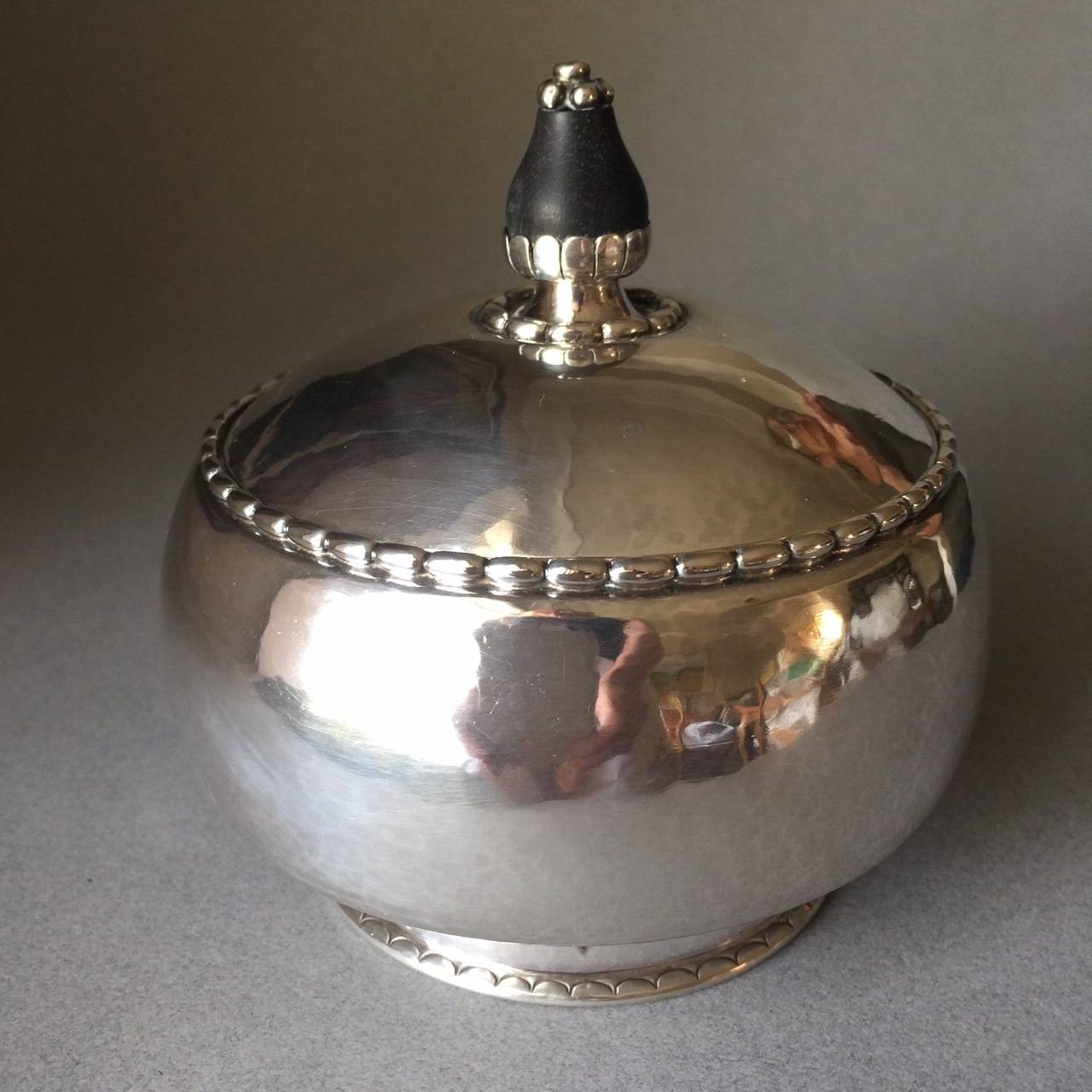Georg Jensen 830 silver tea caddy no. 36.

Very rare to find a Georg Jensen tea caddy in an oval shape. Snug lid with an intricate ebony finial on top with inlaid grape design. Hand-hammered throughout. 

830 silver and early Georg Jensen marks