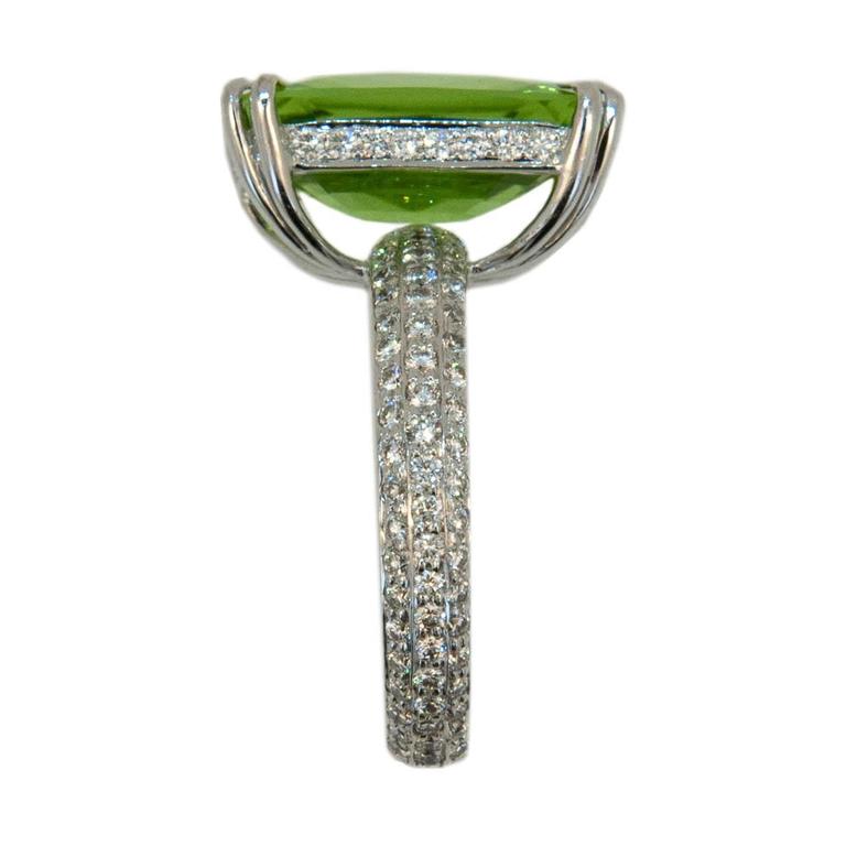 Very fine emerald cut Peridot 8.82cts. Shallow cut stone allows peek through to extravagant diamond shank. Peridot is set in an 18K white gold mounting with split prongs. 153 Round diamonds 1.19cts.twt. Diamonds set on shank all the way around