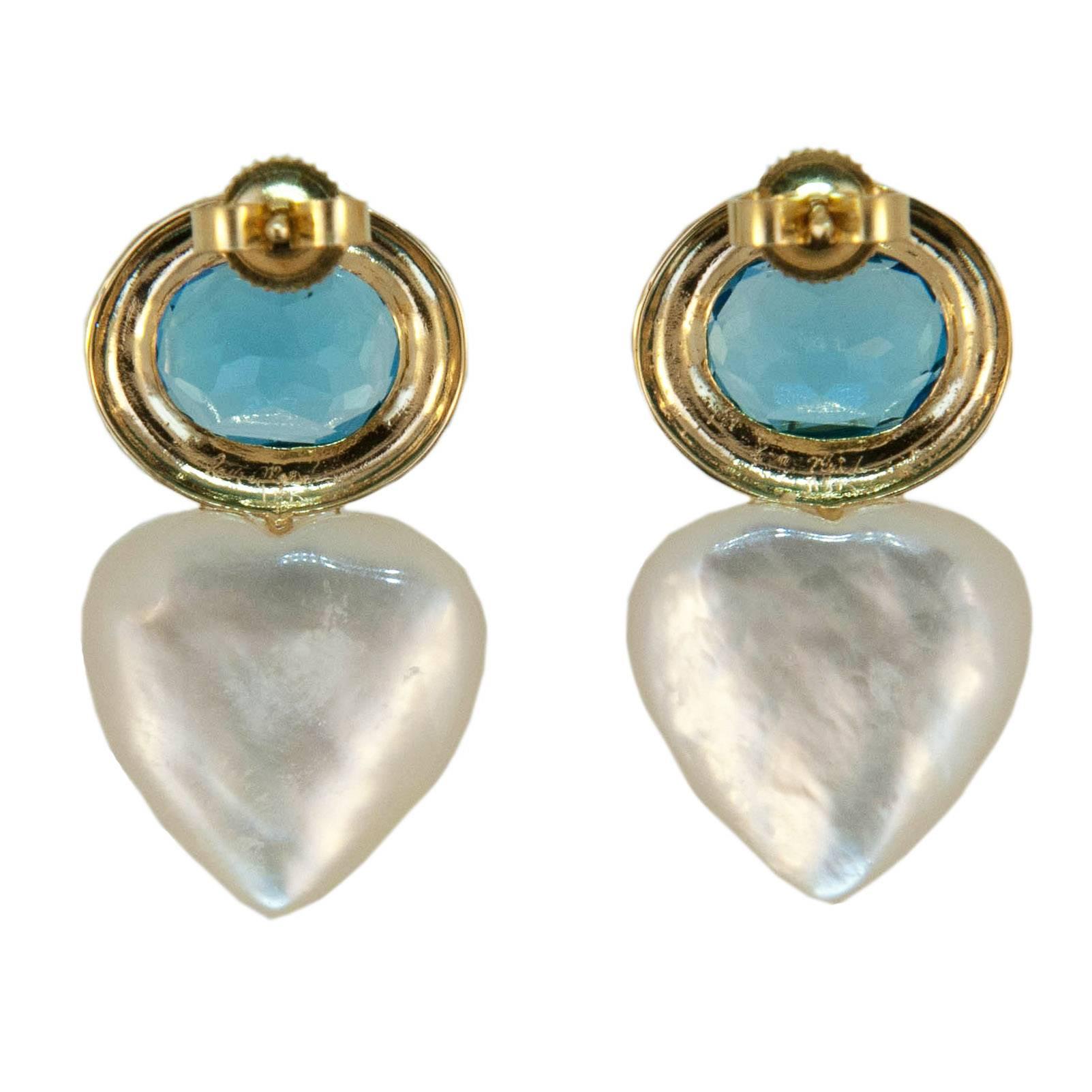 18 karat yellow gold earrings each bezel set with one oval approximate 10x8 millimeter Blue Topaz 6.50 carats total weight. and one 15 millimeter Mother of Pearl heart shape. Friction posts and backs.