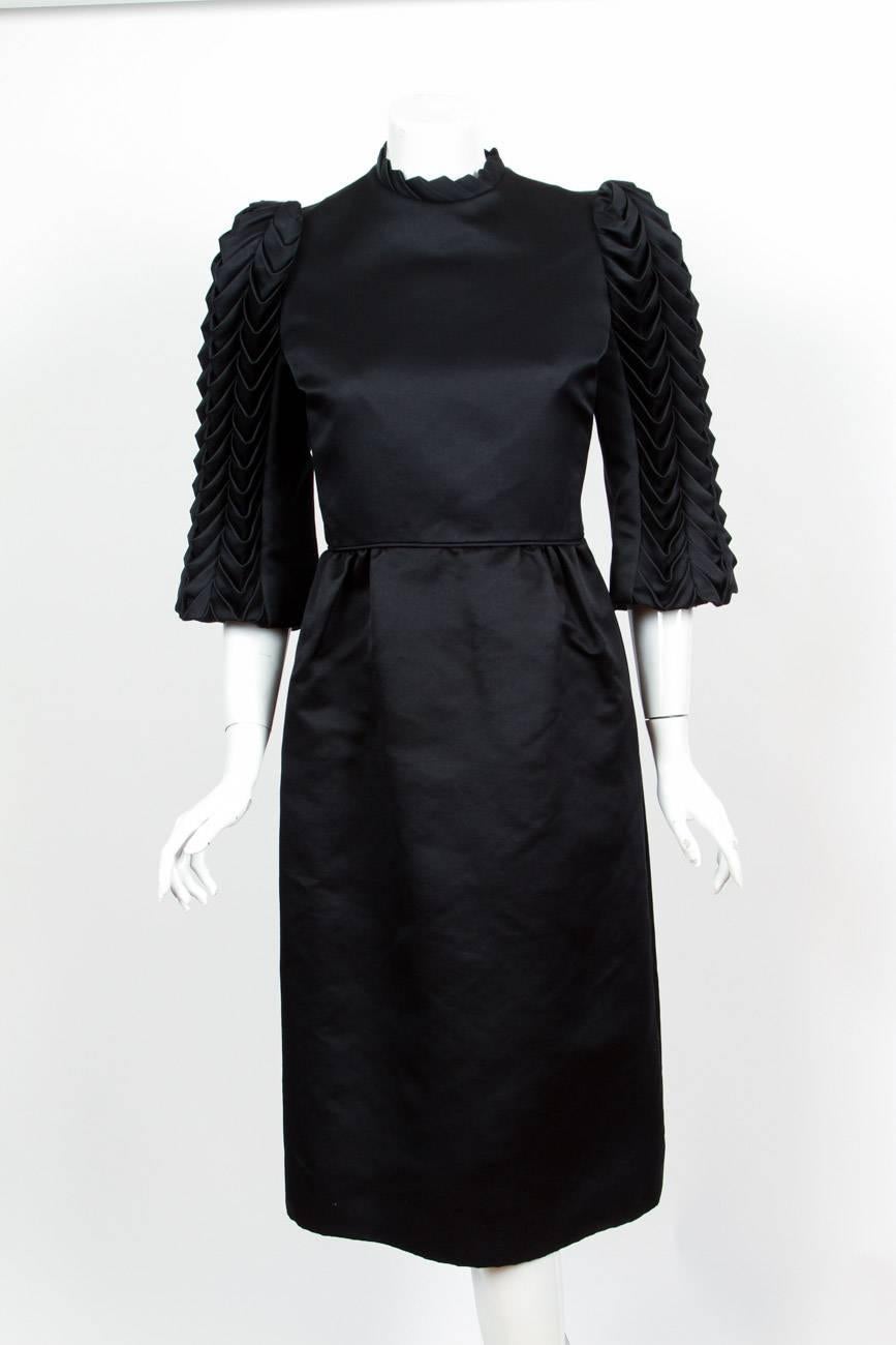 1960’s/1970s Alfred Bosand black satin cocktail dress with chevron pattered accordion/origami 3/4 sleeves. Has two hidden side pockets and fully lined. In excellent condition. No size tag so please consult measurements.
Shoulders – 15”
Waist –