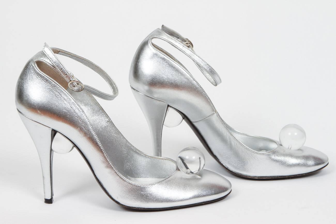 Charles Jourdan silver leather high heels with ankle strap and lucite ball at front of shoe and underneath the heel. In excellent condition with very minor scuffing at the front part of the heel - they were only worn twice. Size 7.