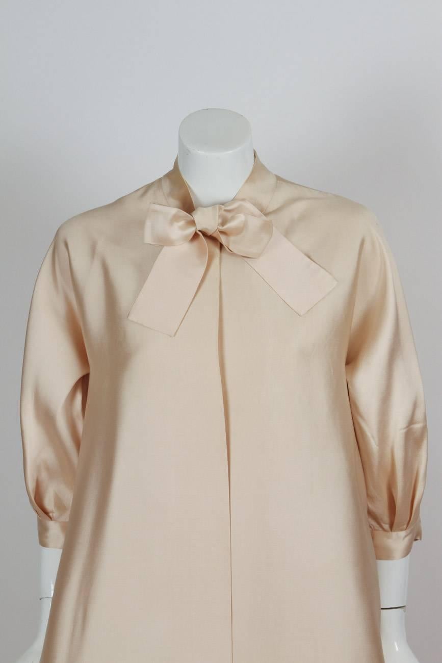 Late 1970’s Madame Gres haute couture champagne-colored silk opera coat
with neck ties, with puffed raglan 3/4 sleeves. The coat is in good to very good condition with some scattered small marks throughout, some imperceptible light stains at the