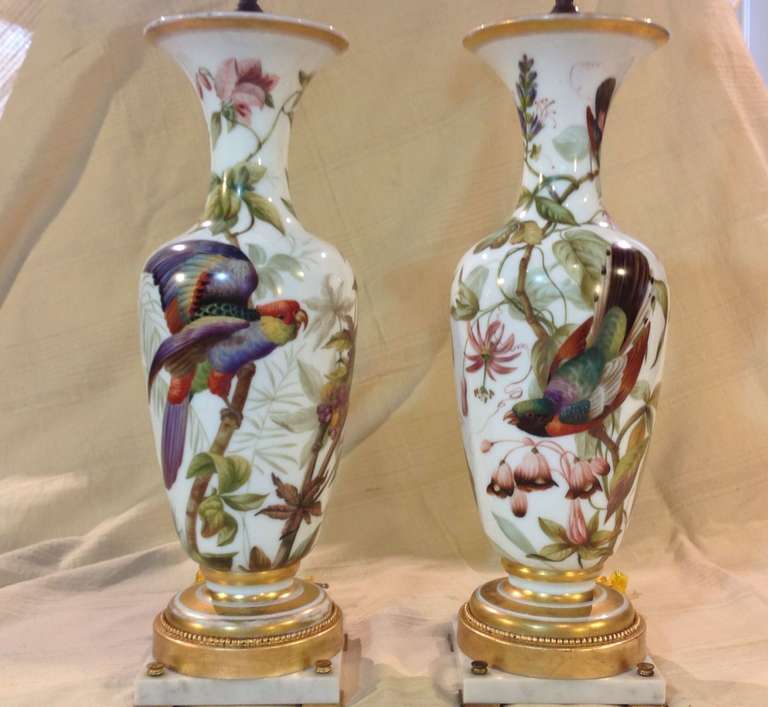 An exceptional pair of baccarat white opaline glass enamel painted vases mounted as table lamps. They are initialed JGP and clearly dated 1849, as shown in photos. Masterfully decorated with exotic birds, fruits, and tropical foliage in vivid yet