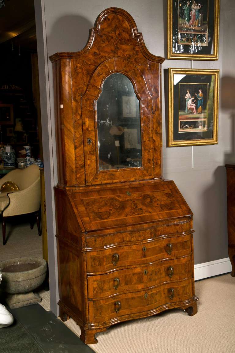 An early 18th century Italian Venetian walnut and burl walnut veneered secretary with serpentine base and mirrored upper door.