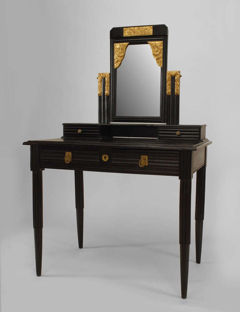 French Art Deco stepped rectilinear dressing table composed of ebonized oak with an upper section supporting a rectangular vanity mirror decorated with floral gilt carved highlights above four drawers, two small and two large.