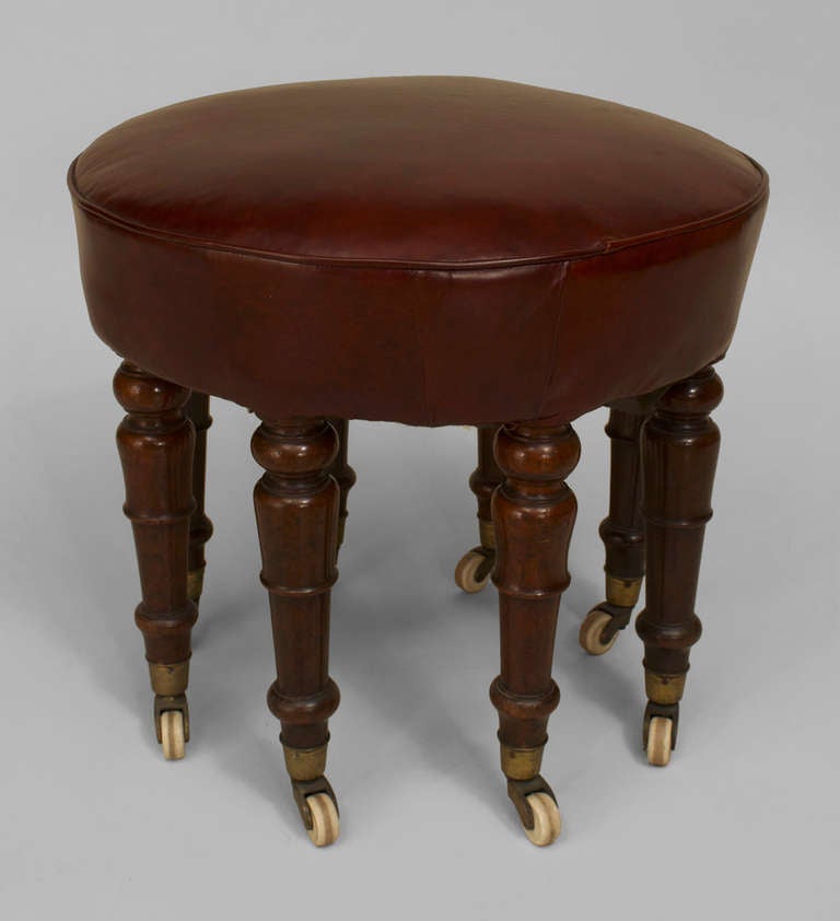 English Victorian (circa 1875) mahogany 8 legged bench on casters with a round dark maroon leather seat.
