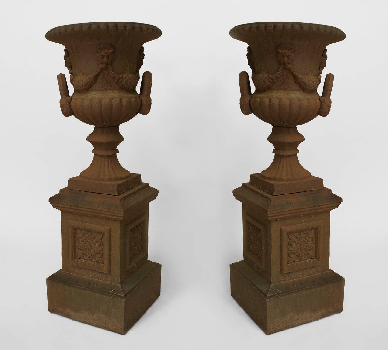 Pair of English Victorian iron urns with festoon design and side handles resting on matching pedestal bases with decorative square panels (Sold AS IS, MISSING PARTS)
