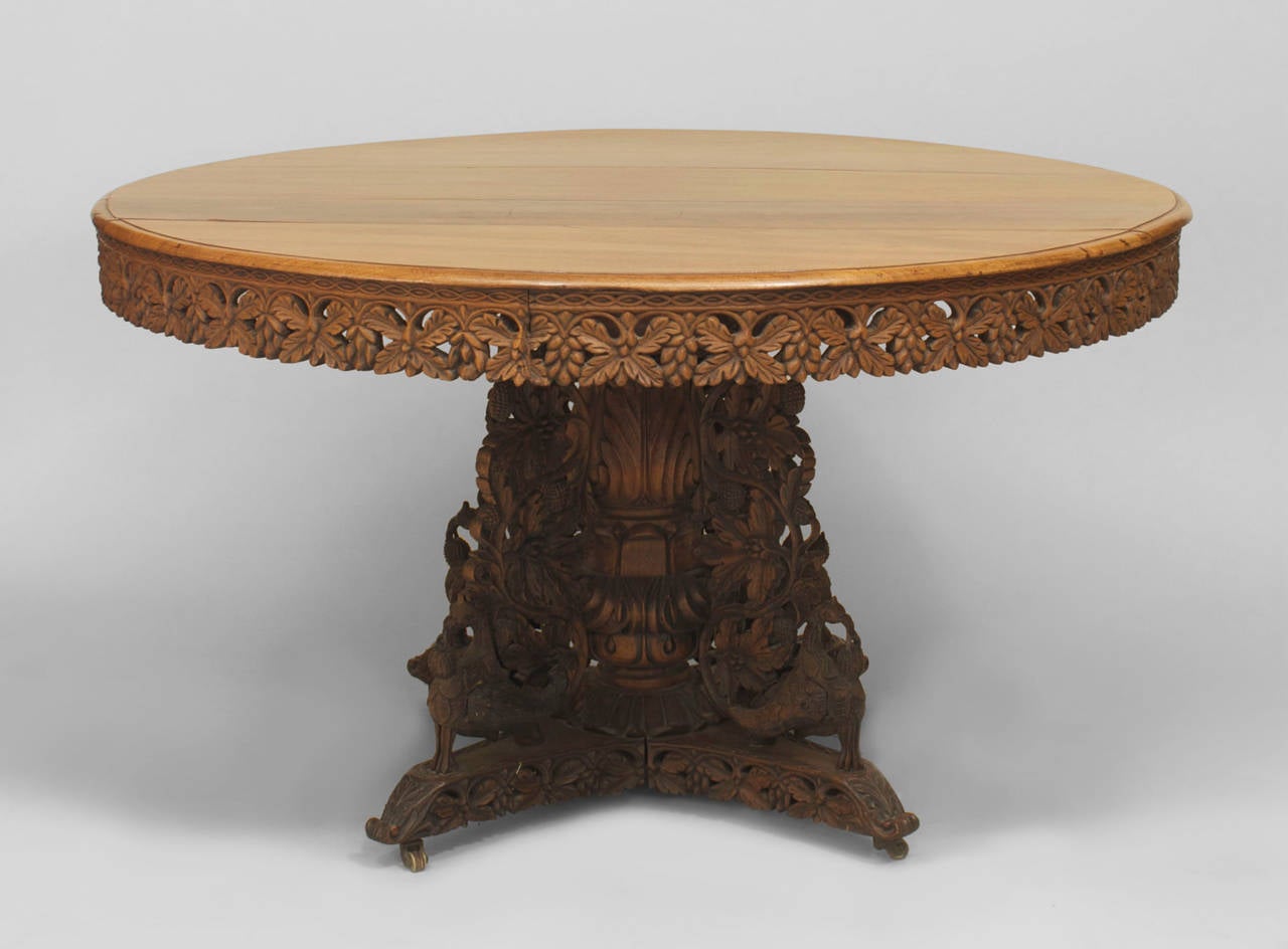 English Anglo-Indian (mid-19th century) teak and padauk circular table with a filigree apron and pedestal base having intricate foliate and aviary carvings.
