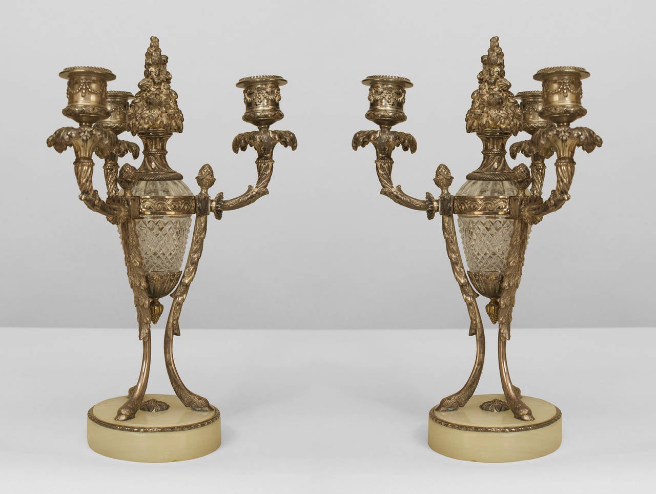 Coppia di candelabri a tre luci in bronzo argentato e vetro tagliato in stile vittoriano francese che poggiano su una base rotonda in onice. (PREZZO A COPPIA)
