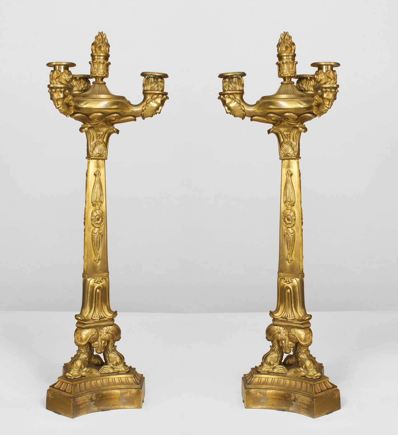 Pair of French Restoration (1st half 19th Cent) gilt bronze three-light candelabra with a flame finial top and resting on 3 dolphin legs over a triangular base