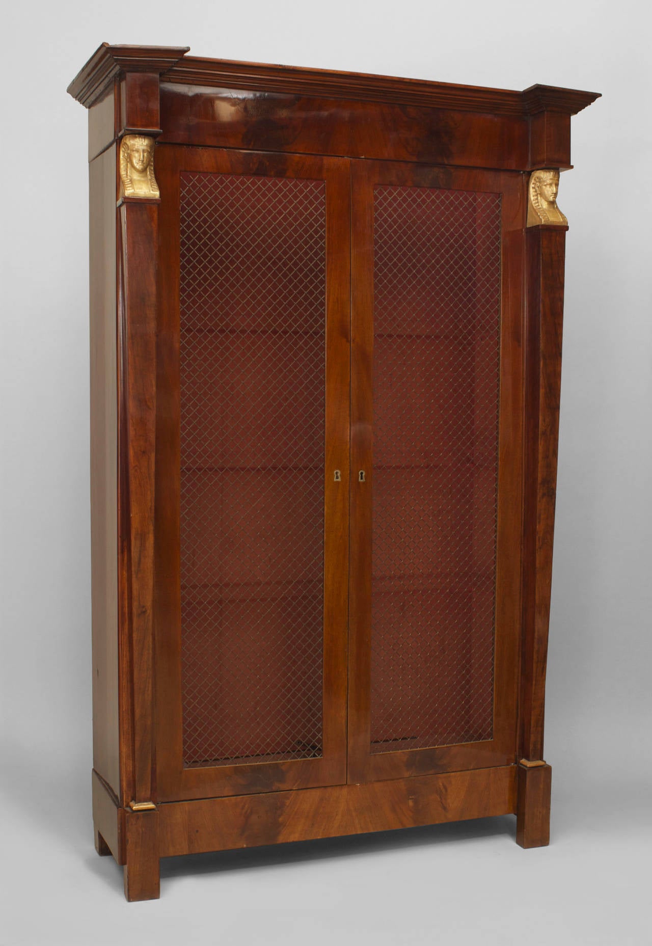 French Empire flame mahogany 2 door biblioth√®que cabinet with with wire mesh and tapered square column sides having gilt bronze trim with classical heads.
