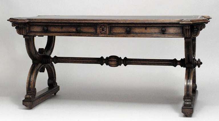 English Late Regency (mid-19th Century) parcel ebonized & oak writing table with black leather inset top above X-trestle legs joined by a stretcher on casters.
