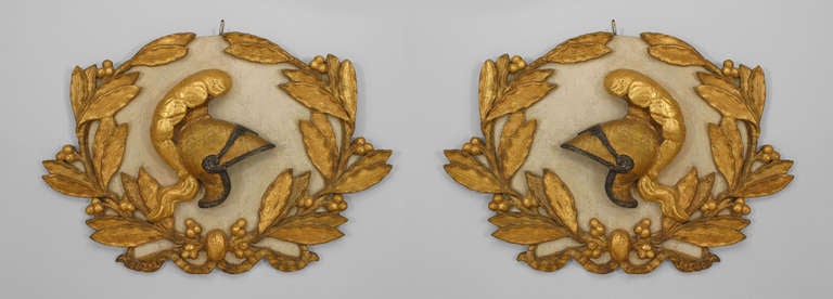 Eighteenth century Italian Neoclassical wall plaques with white painted oval backs adorned with gilt carved helmets and laurel wreaths.
