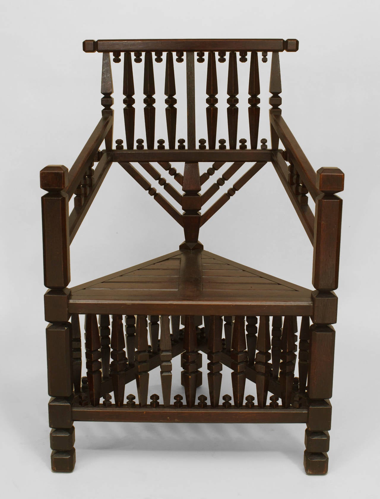 Großer, dunkel gebeizter Sessel aus Eichenholz mit dreieckiger Form und geometrischem Spindel- und Endstückdesign auf Rückenlehne und Bahre.
