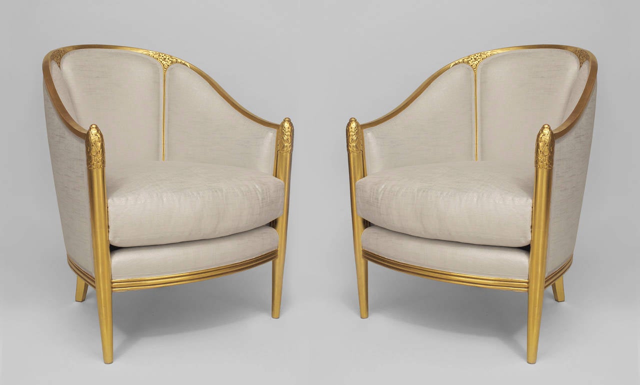 Attributed to Follet, pair of French Art Deco gilt round back club chairs with floral carving on back corners and front arms. Priced per pair.