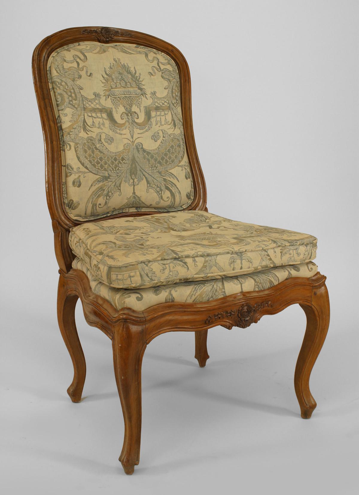 Set of 10 French Louis XV (18th Cent style) walnut side chairs with roset & floral centered carving on back & seat front rail and Fortuny upholstered seat & back.
