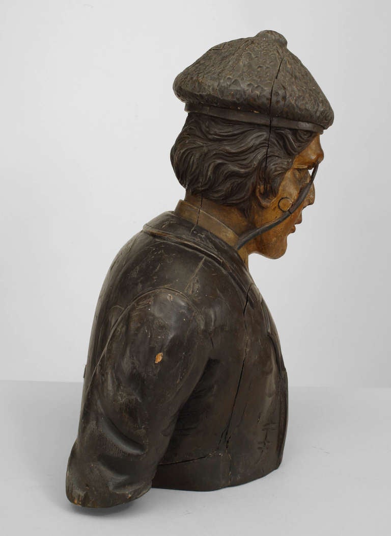 Nineteenth century English carved and painted wooden bust depicting a man clothed in English or Scottish country attire wearing a monocle and a decorative flower in his lapel.