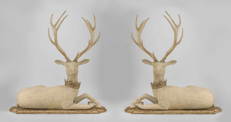 Pair of life-sized, left and right nineteenth century English country style sculptures carved in the form of horned stags painted white and adorned with crown collars as they recline upon round silver gilt bases.