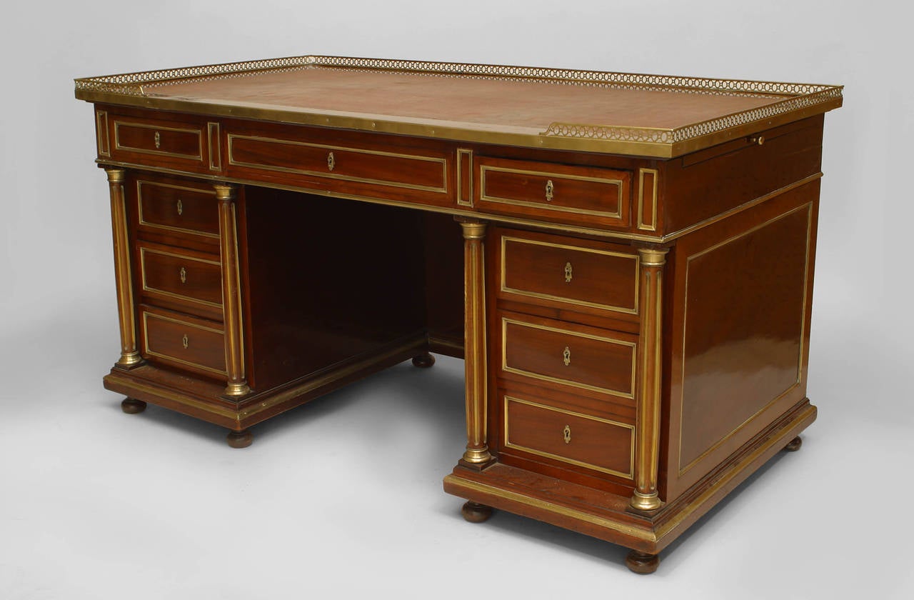 French Louis XVI style (19th Century) mahogany and bronze trimmed fluted leg kneehole desk with gallery.
