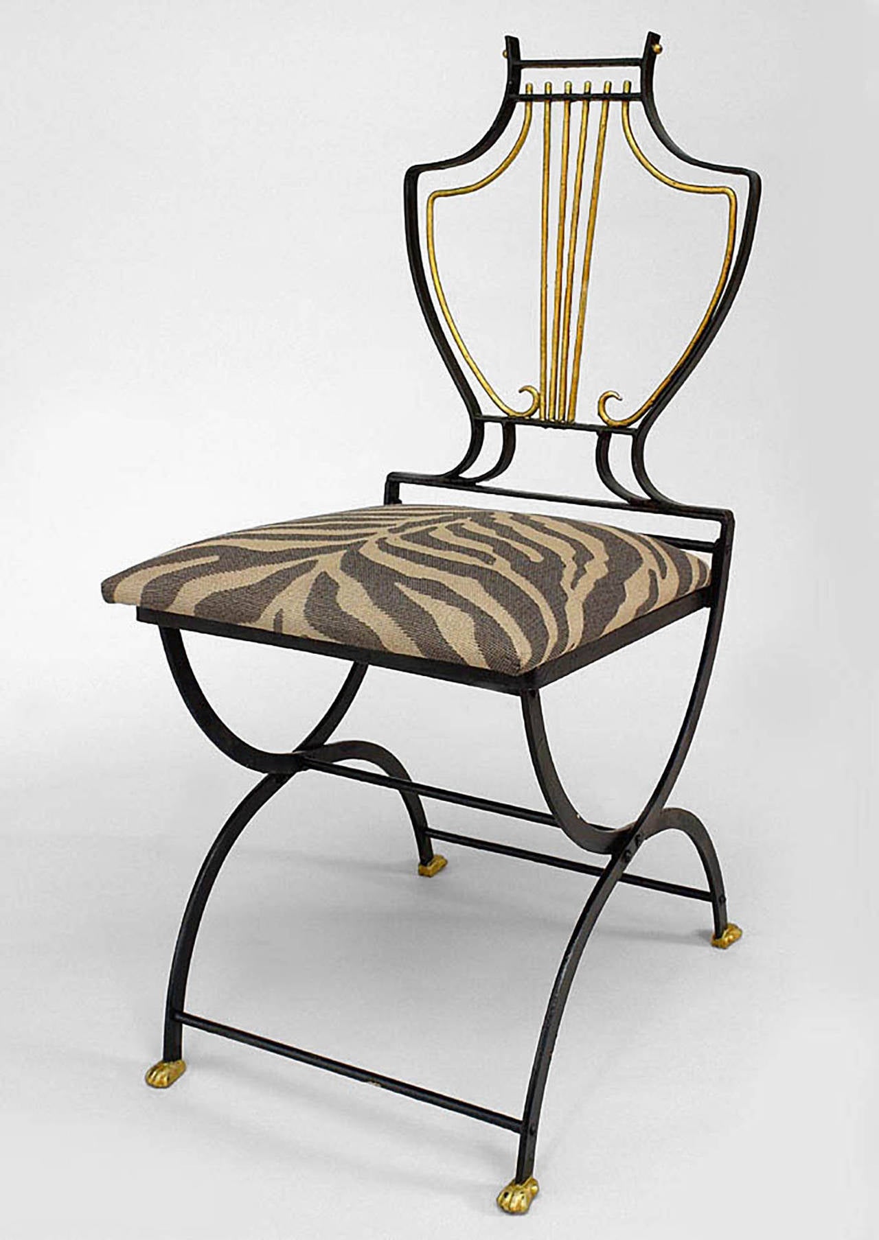 Ensemble de 4 chaises d'extérieur Art Moderne en métal peint noir et or avec dossier en forme de lyre et assise rembourrée.
