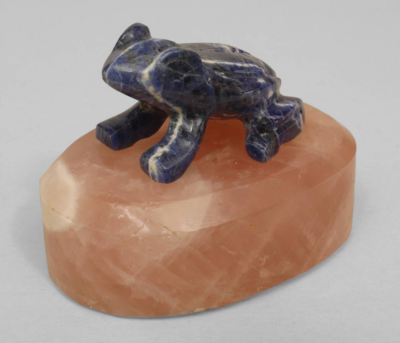 Moderna figura di rana in lapis che poggia su una base ovale in quarzo rosa.
