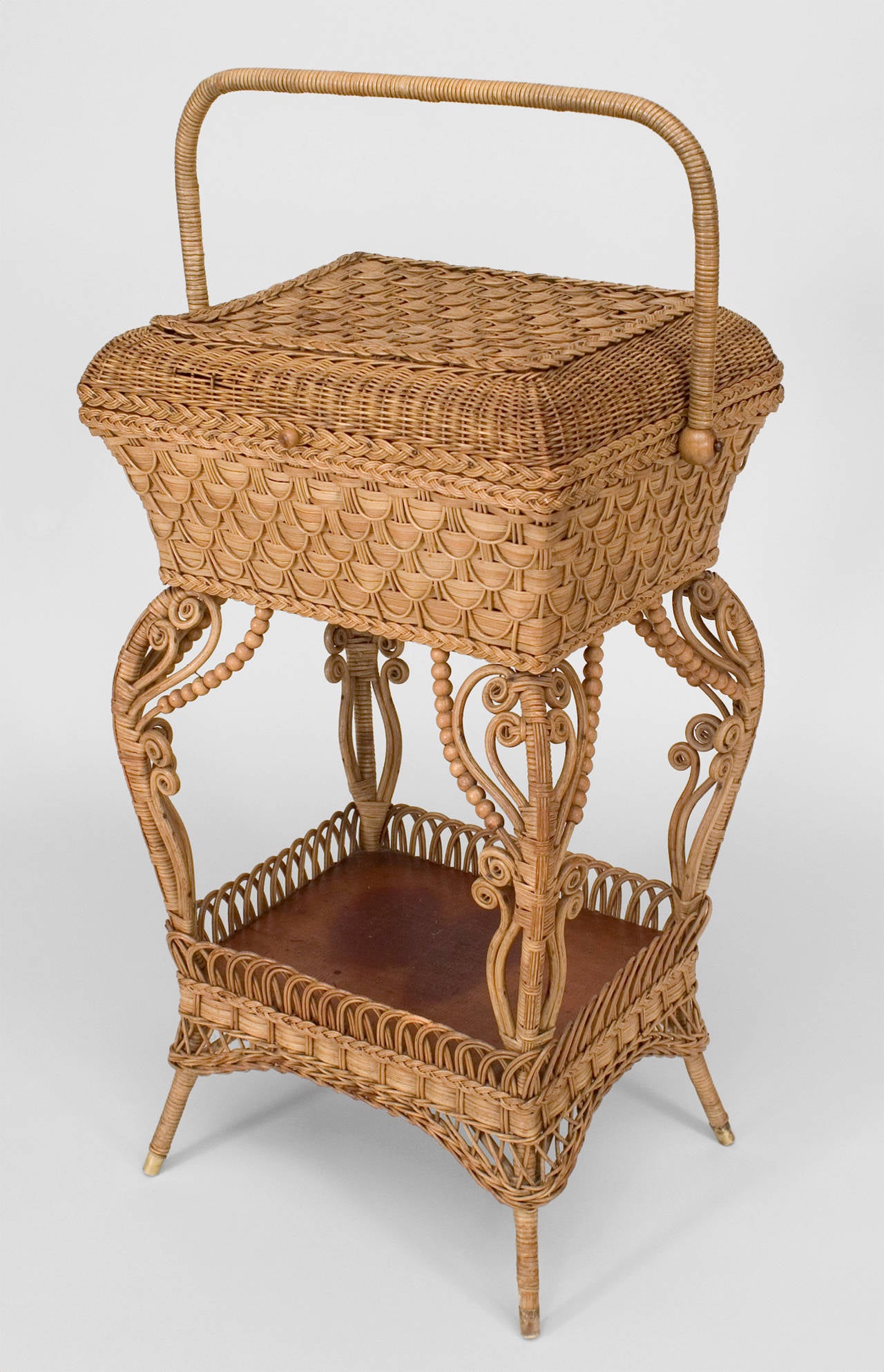 American Victorian natural wicker sewing table with woven flip top box with handle above a bottom shelf with gallery and scroll decorative trim (HEYWOOD WAKEFIELD label)
