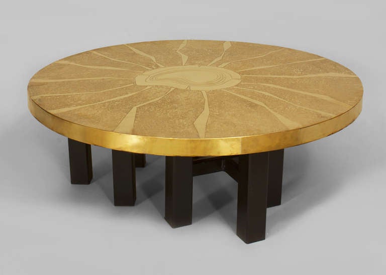 1970's Belgian coffee table by Lova Creation. This table features a round brass top with an etched sunburst design resting upon a nine-legged, ebonized base.