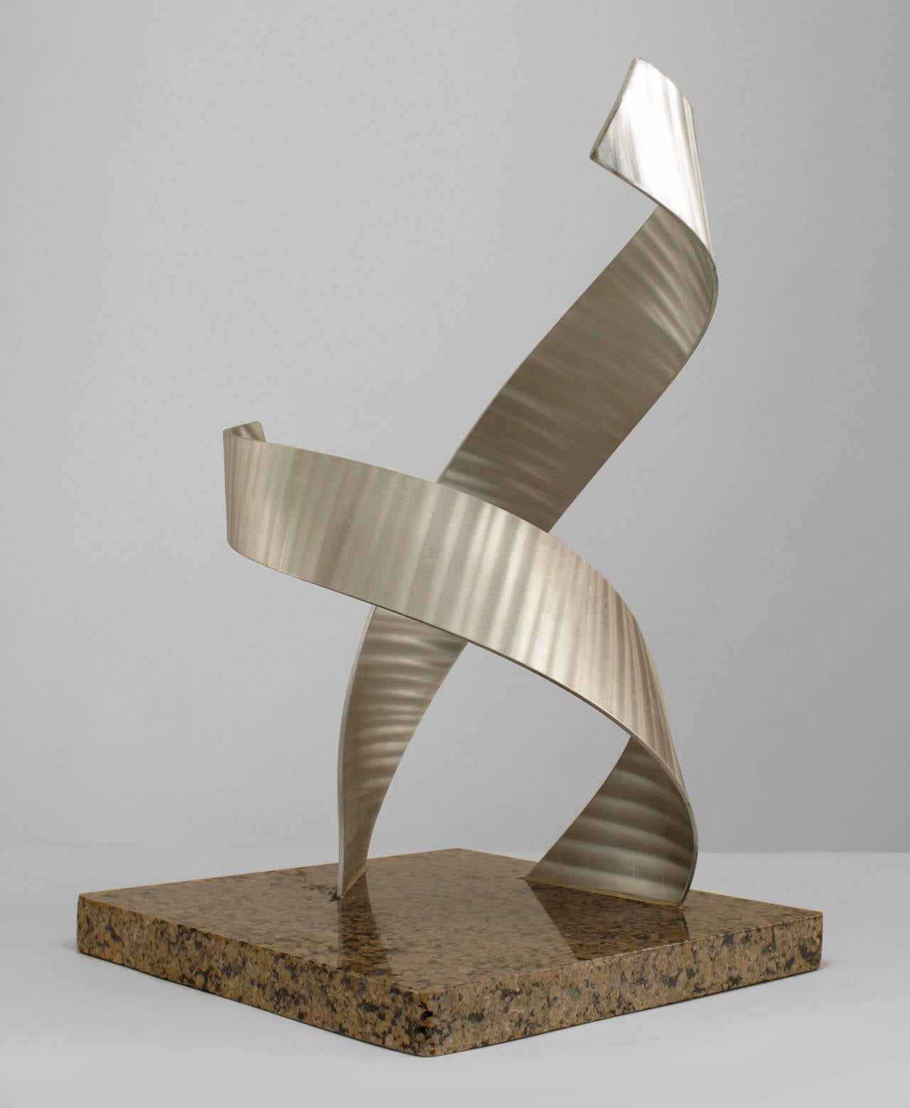 Contemporary American sculpture of two abstract, intertwined aluminum scroll
forms rising from a granite base.