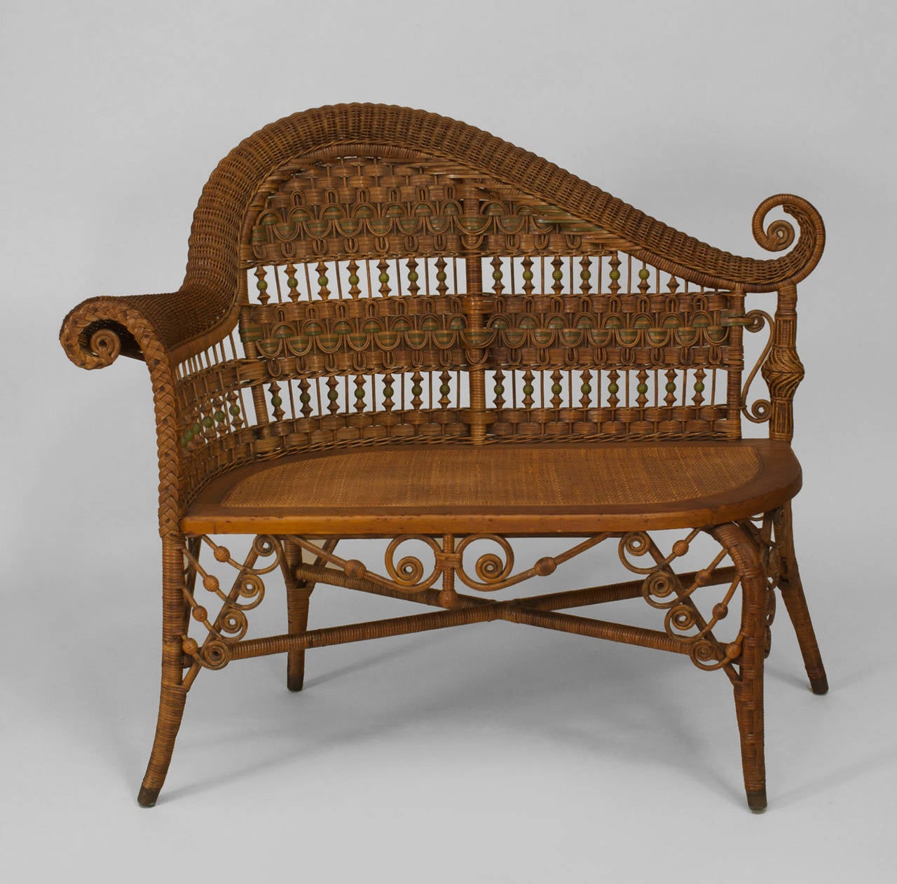 Attributed to Heywood Wakefield, a 19th century American natural wicker and green decorated trimmed recamier (or photographer's bench) designed with scroll and spindle designs and a woven seat.
