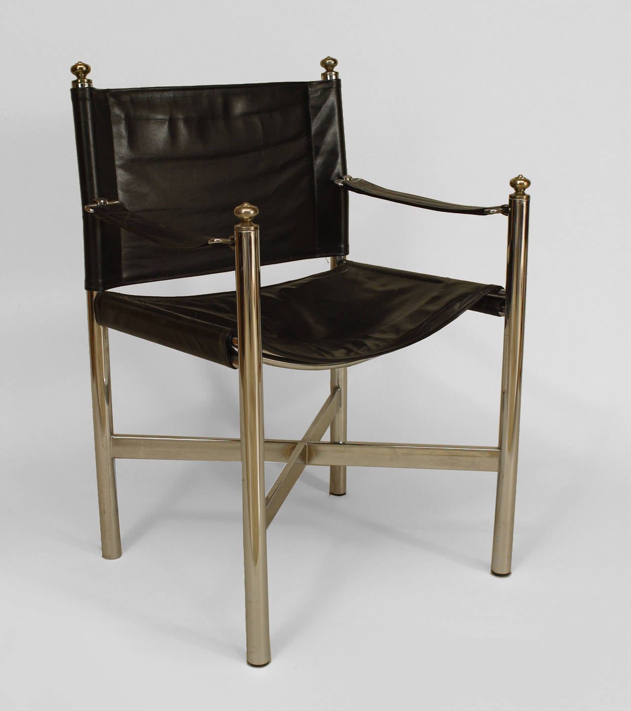 Pair of American Art Moderne chrome framed, brass trimmed arm chairs with
black leather seat, back and arms.